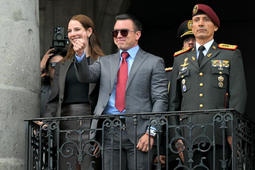 El presidente reelegido de Ecuador, Daniel Noboa, saluda a sus simpatizantes, acompañado por su esposa, Lavinia Valbonesi (izq.), y el jefe de la Casa Militar Presidencial, Milton Rodríguez, desde un balcón del Palacio Presidencial de Carondelet durante la ceremonia de cambio de guardia en Quito el 15 de abril de 2025.&nbsp;
