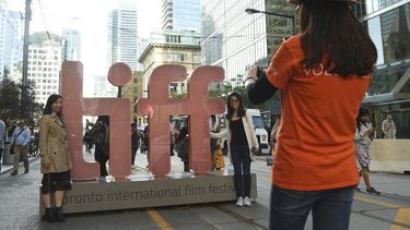 En esta fotograf&iacute;a del 5 de septiembre de 2019, un voluntario toma una foto a dos personas junto a una reproducci&oacute;n del logotipo del Festival Internacional de Cine de Toronto.