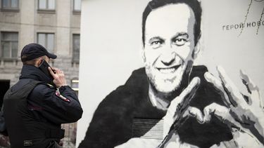 Un agente de policía habla por teléfono cerca de un grafiti con la imagen del encarcelado líder opositor ruso Alexei Navalny, en San Petersburgo, Rusia, el 28 de abril de 2021.&nbsp;