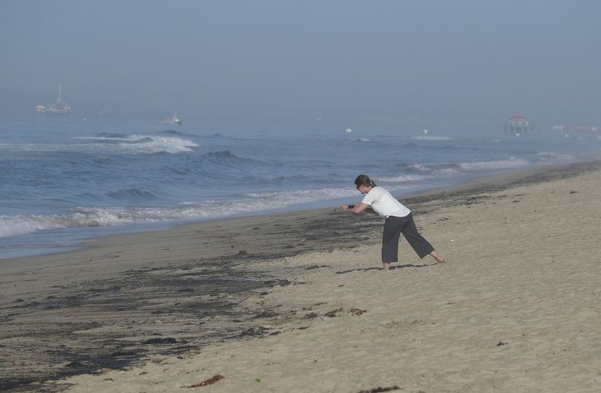 Una mujer toma fotos del daño causado por el derrame petrolero en Huntington Beach, California el 3 de octubre del 2021.&nbsp;