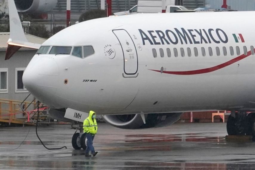 Un trabajador caminando frente a un Boeing 737 Max 9 con el logotipo de Aeroméxico.