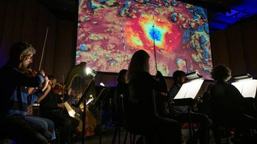 Los miembros de la Filarmónica Nacional ensayan Cosmic Cycles, A Space Symphony del compositor Henry Dehlinger, en Capital One Hall en Arlington, Virginia, el 11 de mayo de 2023. Las imágenes alucinantes del espacio han sido la inspiración musical.