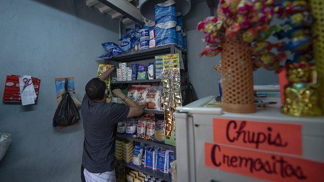 Rosmer Díaz, un empleado público cuyo trabajo está paralizado por la cuarentena por el COVID-19, arregla mercadería dentro de una pequeña tienda que instaló en lo que solía ser el área de basura de un edificio de viviendas públicas en el barrio San Agustín de Caracas, Venezuela, el domingo 23 de agosto de 2020.