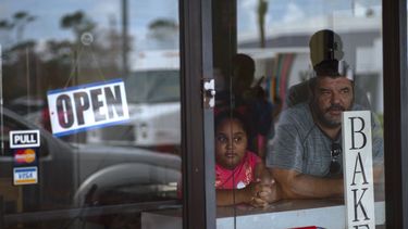 Un hombre y una niña miran hacia fuera en uno de los establecimientos que presta servicios en Freeport tras el paso del huracán Dorian por Bahamas.