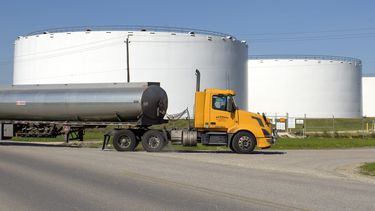 Un cami&oacute;n sisterna pasa frente a dep&oacute;sitos de combustible.