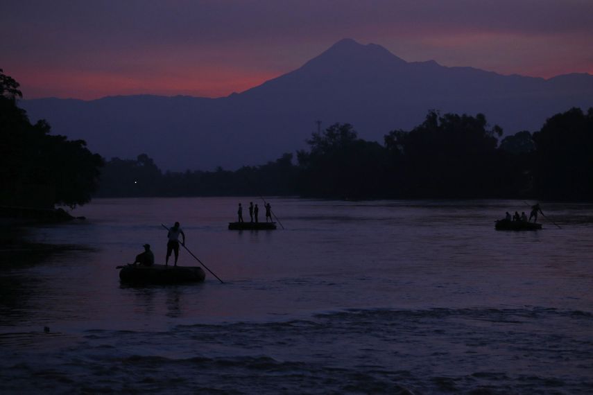 En esta imagen de archivo, tomada el 18 de junio de 2019, balsas llevan a personas y bienes de una orilla a otra del río Suchiate, entre Tecún Umán, en Guatemala, y Ciudad Hidalgo, en México, con el volcán Tacana de fondo al amanecer.&nbsp;&nbsp;