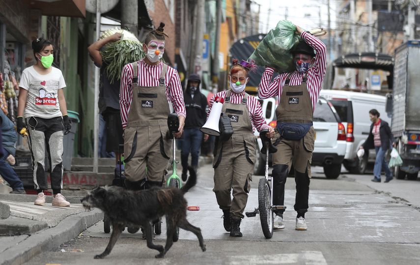 Los miembros del grupo Circo Encuentro caminan por una calle con alimentos donados que recibieron a cambio de sus presentaciones en Bogot&aacute;, Colombia, el s&aacute;bado 4 de julio de 2020.&nbsp;