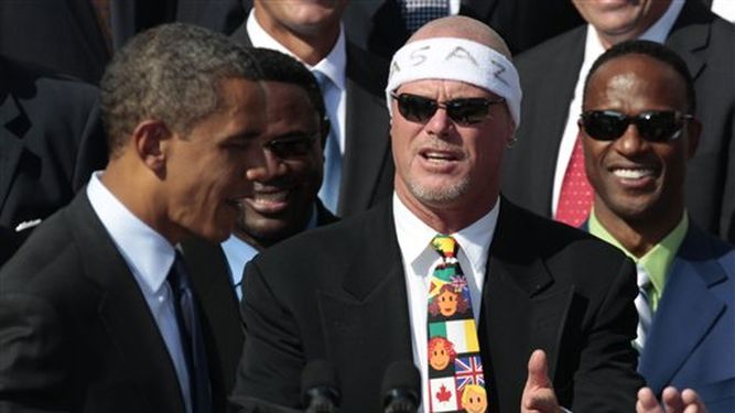En esta foto de archivo del 7 de octubre de 2011, el presidente Barack Obama, está al lado del ex quarterback de los Bears de Chicago, Jim McMahon, usando una banda en la cabeza, cuando honró al equipo campeón del Super Bowl XX de 1985 en la Casa Blanc
