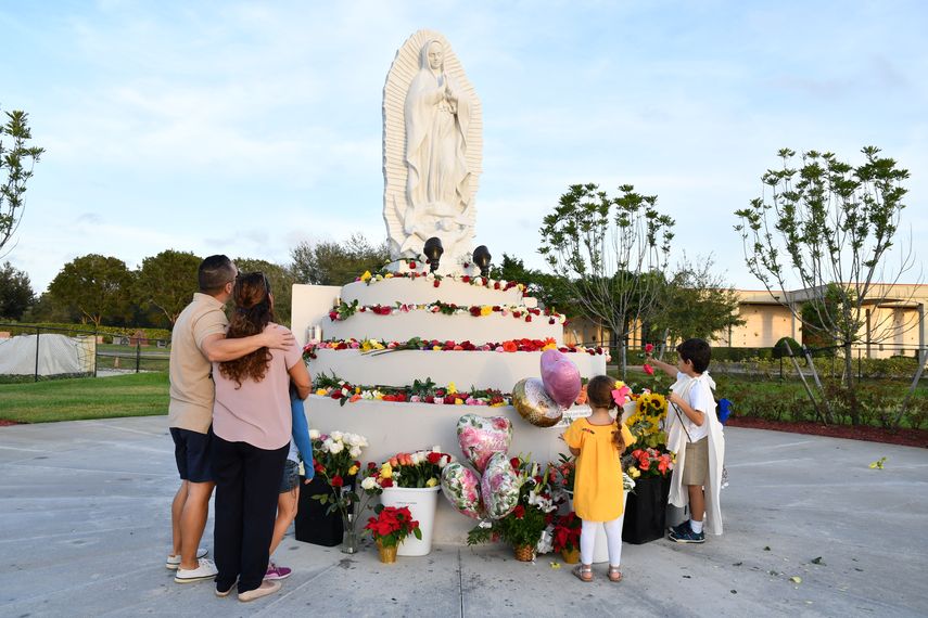 Las familias depositan flores a los pies de la imagen de la virgen.