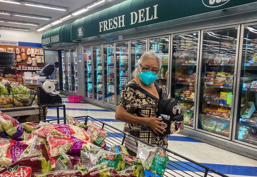 Una mujer observa con detenimiento los precios de alimentos en un supermercado.