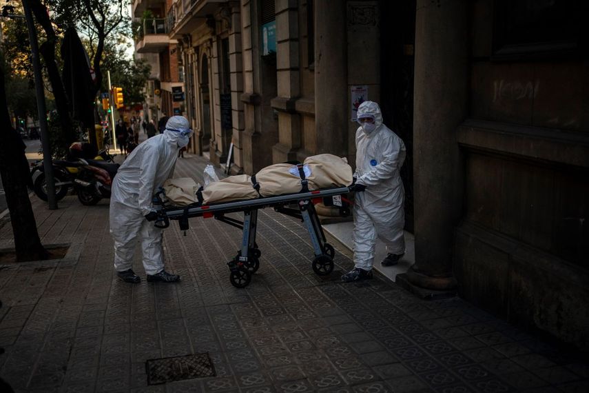 Trabajadores funerarios trasladan el cuerpo de un anciano fallecido por COVID-19 tras retirarlo de una residencia en Barcelona, España, el viernes 13 de noviembre de 2020. Los trabajadores de funerarias vuelven a verse sobrepasados por un brote de coronavirus en residencias y hospicios de toda Europa, lo que ha sumido a las autoridades y trabajadores de residencias en una carrera contrarreloj hasta que puedan comenzar las vacunaciones.&nbsp;