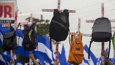 Varios jóvenes sostienen unas cruces con mochilas en honor a los estudiantes que murieron en las pasadas manifestaciones contra Daniel Ortega.