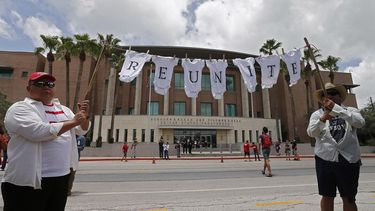 Manifestante sostienen una cuerda con ropa de bebés en la que se lee la palabra reunir durante una protesta contra la política migratoria de tolerancia cero del Gobierno de Trump.
