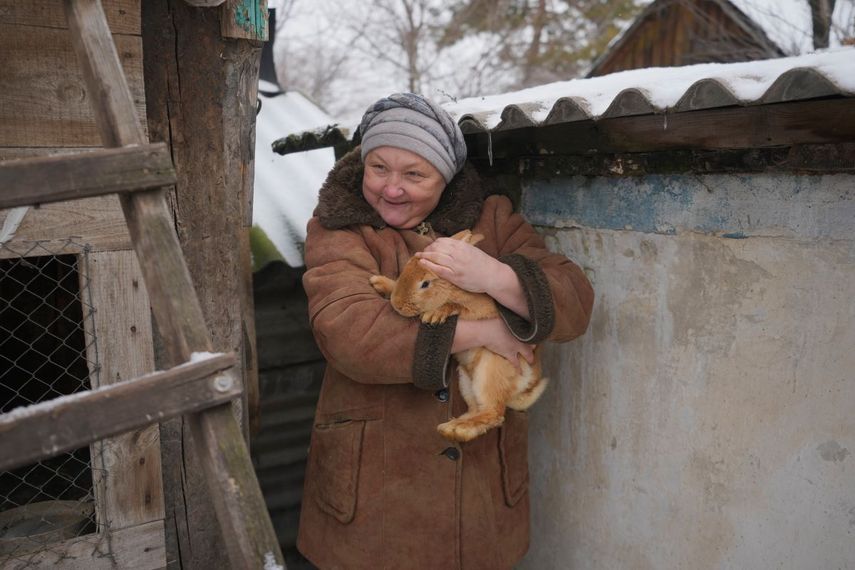 Olga, una de las 16 residentes que todavía viven en una aldea en el frente, carga un conejo mientras habla con periodistas en el patio de su casa no lejos del frente en la región de Luhansk, en el este de Ucrania, el viernes 28 de enero de 2022.