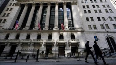 Dos personas caminas frente a la sede de Wall Street en Nueva York.