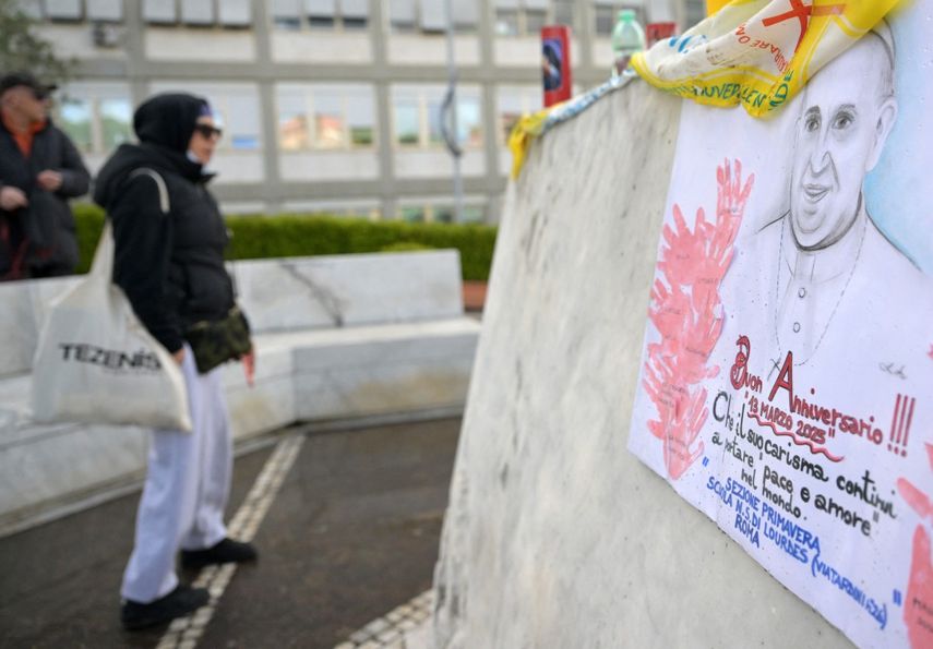 Una imagen muestra un retrato del papa Francisco dibujado por niños de la escuela en la estatua de Juan Pablo II afuera del hospital Gemelli, donde está hospitalizado desde el 14 de febrero de 2025