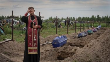 Un sacerdote ora por los restos de civiles no identificados antes de que sean enterrados el jueves 11 de agosto de 2022 en Bucha, en las afueras de Kiev, Ucrania.