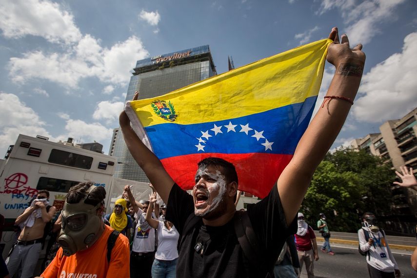 Un hombre levanta las manos con un abandera de Venezuela en medio de una protesta opositora al régimen de Nicolás Maduro, el jueves 6 de abril de&nbsp;2017, en Caracas.