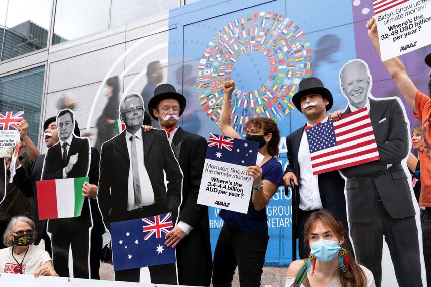 Activistas que sostienen imágenes en cartón del presidente estadounidense Joe Biden, el primer ministro australiano Scott Morrison y el premier italiano Mario Draghi protestan frente a la sede del Fondo Monetario Internacional durante las reuniones anuales entre el FMI y el Banco Mundial, el miércoles 13 de octubre de 2021, en Washington.
