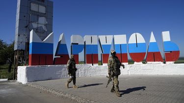 Soldados rusos pasan frente al nombre de la ciudad Mariúpol repintado con los colores de la bandera rusa en la entrada de Mariúpol, en Donetsk, en el este de Ucrania, el domingo 12 de junio de 2022.&nbsp;