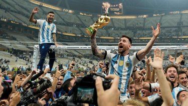 Lionel Messi celebra con el trofeo de campeón mundial con los hinchas de Argentina tras la victoria ante Francia por penales en la final del Mundial, el domingo 18 de diciembre de 2022, en Lusail, Catar.&nbsp;