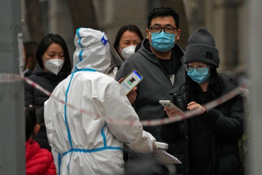 Un hombre muestra su código QR de control de salud mientras él y otras personas hacen fila para hacerse pruebas de rutina de COVID-19 en Pekín, China.