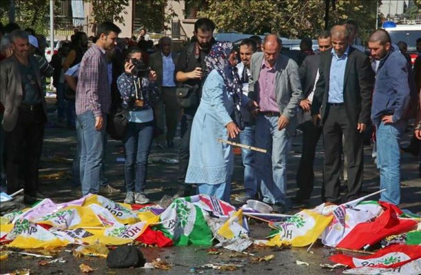 Ciudadanos turcos observan los cuerpos de las víctimas del atentado de este sábado en Ankara (Turquía) cubiertos por banderas. (EFE)
