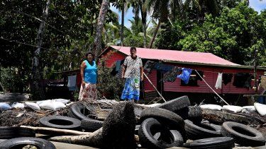 Esta fotografía tomada el 13 de diciembre de 2022 muestra a la residente Lavenia McGoon (derecha) con un miembro de su familia frente a un malecón improvisado con llantas de goma viejas para evitar la erosión, afuera de su casa frente a la playa en un pueblo de la ciudad costera de Togoru, a unos 35 kilómetros. de la capital de Fiji, Suva.  