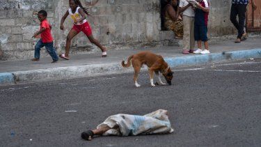Las piernas de un hombre descuartizado sobresalen de una bolsa tirada en una calle donde hay niños jugando y perros, en el vecindario de Colinas de La Florida, en Guayaquil.