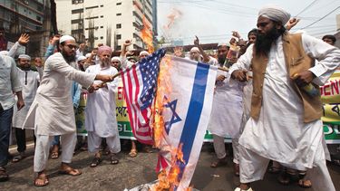 Miembros del califato islámico Andolon corean lemas mientras queman una bandera de Estados Unidos y otra de Israel durante una manifestación.