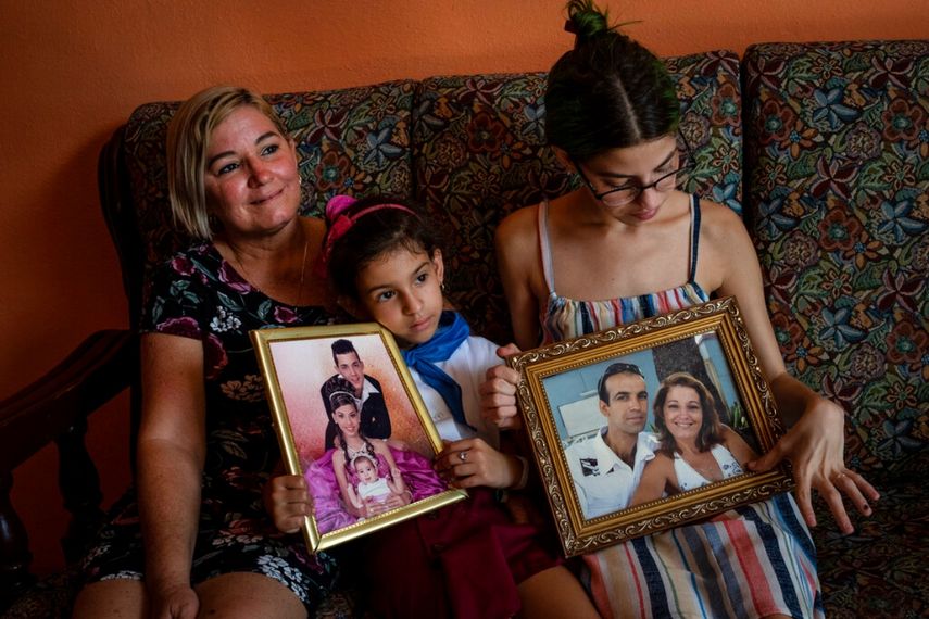 Danmara Triana (izquierda), con sus hijas Alice (centro) y Claudia, muestran fotos suyas con su hermano y su padres, quienes se mudaron a EEUU en 2015, en su casa en Cienfuegos, Cuba.