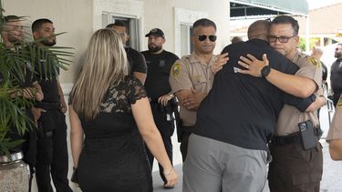Compañeros oficiales de la Policía de Miami-Dade se abrazan al llegar al funeral de César Echy Echaverry.