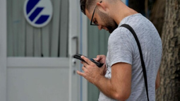 Un joven frente a un cartel de Etecsa en Cuba.