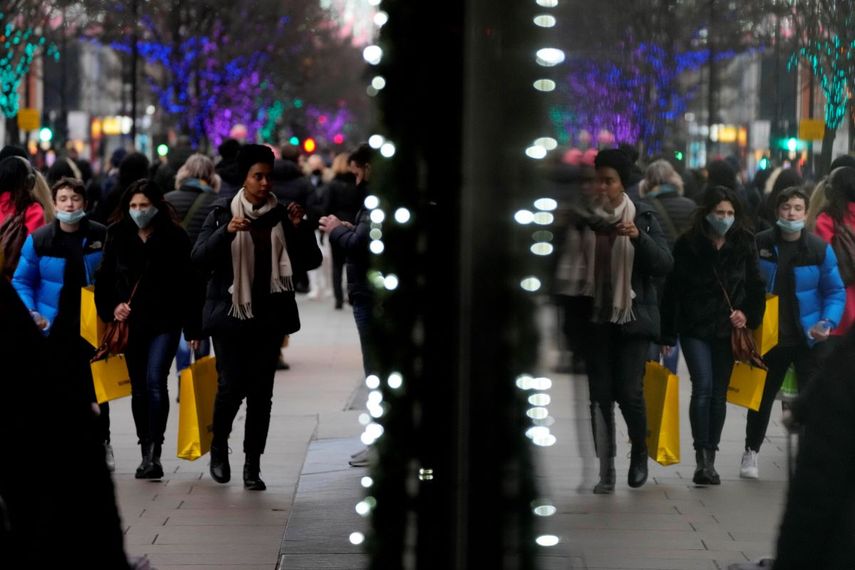 Compradores se reflejan en una ventana mientras caminan por Oxford Street, la calle para compras más ajetreada de Europa, en Londres, el jueves 23 de diciembre de 2021.