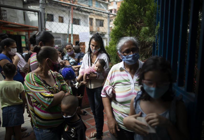 Varias mujeres y niños, con mascarillas para protegerse del coronavirus, aguardan su turno el viernes 20 de noviembre de 2020 durante una campaña de vacunación contra otras enfermedades organizada por el Ministerio de Salud, en el vecindario El Valle, en Caracas, Venezuela.