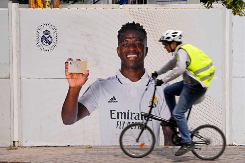 Un ciclista pasa frente a un afiche de Vinicius Junior, el delantero brasileño del Real Madrid, frente al estadio Santiago Bernábeu, el lunes 22 de mayo de 2023 en Madrid.