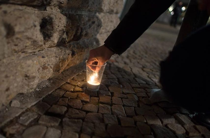 Una persona enciende una vela en Berlín para orar por las víctimas del atentado múltiple ocurrido este viernes en París (EFE)
