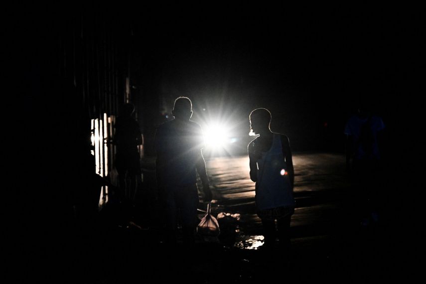 Una pareja de cubanos camina por una calle durante un apagón nacional causado por una falla de la red eléctrica en La Habana el 15 de marzo de 2025.AFP