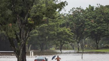 El propietario de un coche, prácticamente sumergido, intenta rescatar objetos personales de su interior, en una avenida afectada por las inundaciones provocadas por el paso del huracán&nbsp;Lane&nbsp;en Hilo, Hawái, Estados Unidos.&nbsp;
