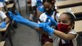 Una estudiante con máscara se pone guantes de plástico como medida de precaución en medio de la propagación del nuevo coronavirus durante una clase en La Habana, Cuba, el lunes 2 de noviembre de 2020. Decenas de miles de escolares regresaron a clases el lunes en La Habana por primera vez desde que la pandemia de coronavirus llevó a las autoridades a cerrar la isla en abril.
