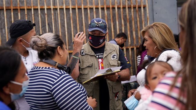 El activista Robert Vivar (centro) habla en Tijuana (México) con migrantes que esperan cruzar la frontera para solicitar asilo en EEUU.