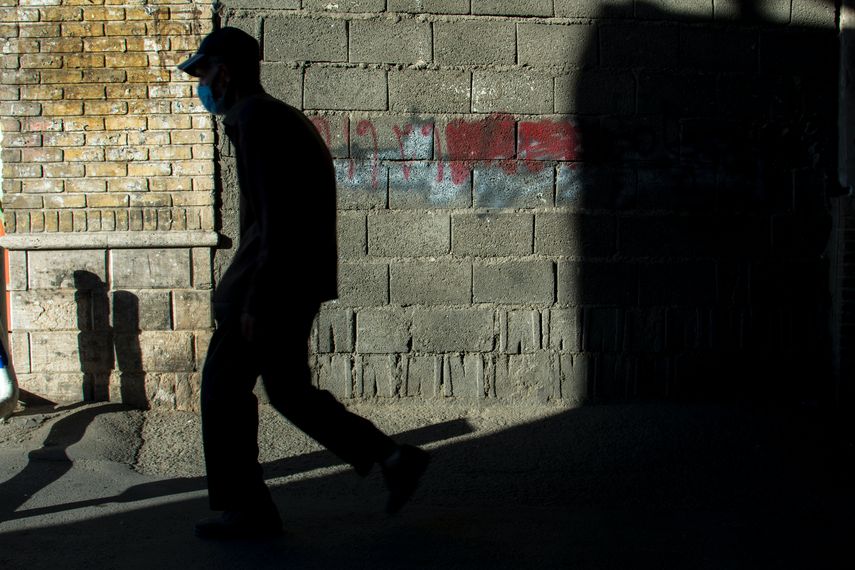 Una persona camina por una calle con una mascarilla.&nbsp;