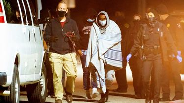 Varias personas esposadas en pares son subidas a camionetas el jueves 4 de diciembre de 2020 durante una investigación de la policía sobre un posible caso de contrabando humano, en Houston.&nbsp;