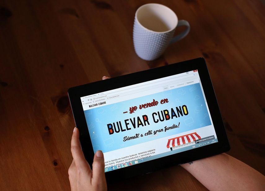 Una joven posa mostrando en una tableta la página de Bulevar Cubano.