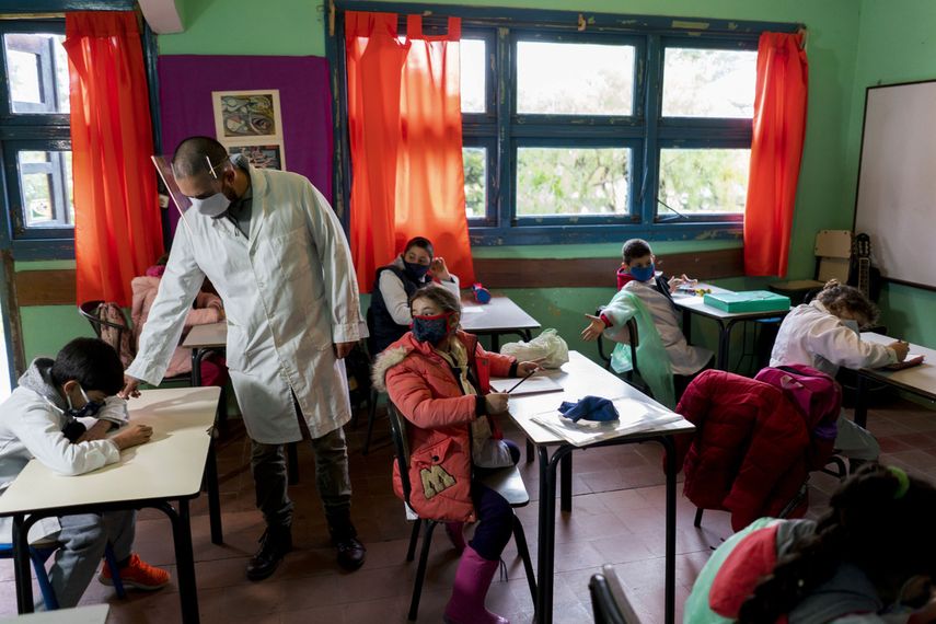 Usando una mascarilla en medio de la pandemia del nuevo coronavirus, un maestro dirige su clase en el primer d&iacute;a de vuelta a la escuela rural cerca de Empalme Olmos, Uruguay, el lunes 1 de junio de 2020