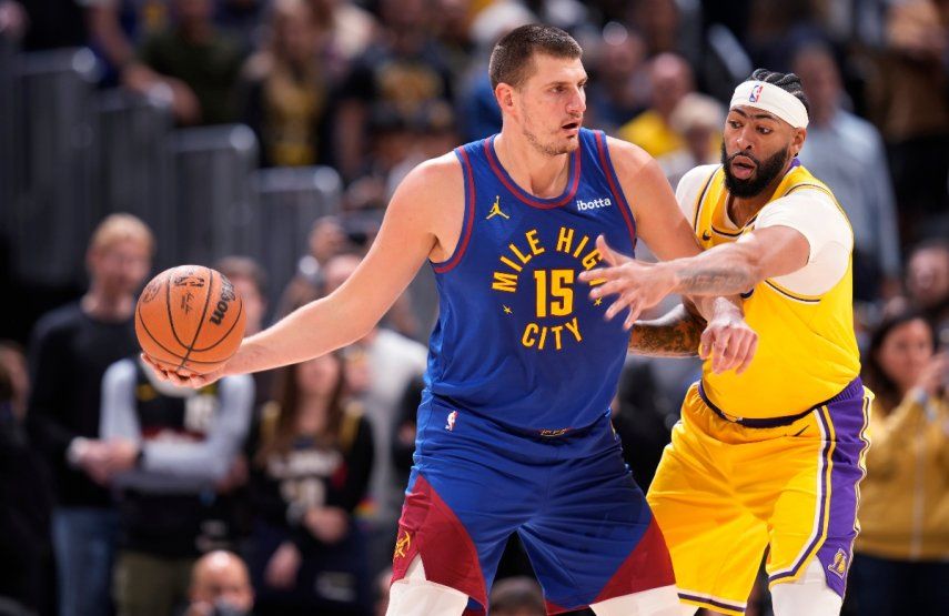 El serbio Nikola Jokic, pívot de los Nuggets de Denver, busca enviar un pase frente a Anthony Davis, alero de los Lakers de Los Ángeles, en el partido inaugural de la campaña de la NBA, el martes 24 de octubre de 2023 