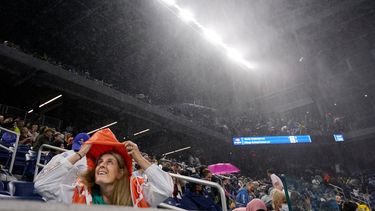 Una aficionado se cubre de la lluvia en el estadio Louis Armstrong durante el partido entre Kevin Anderson y Diego Schwartzman por la segunda ronda del US Open