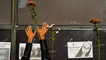 Una mujer coloca flores en la fachada de la Fiscalía General de la República durante una protesta por la desaparición de Debanhi Escobar y otras mujeres.