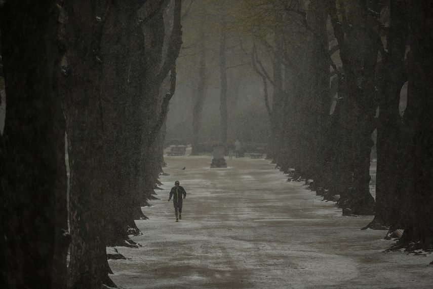 Un hombre corre bajo la nieve en el parque Cinquantenaire en un frío día de primavera en Bruselas, el martes 6 de abril de 2021. Los belgas se despertaron el martes ante una pequeña nevada en la capital, un tiempo poco habitual para esta época del año.&nbsp;