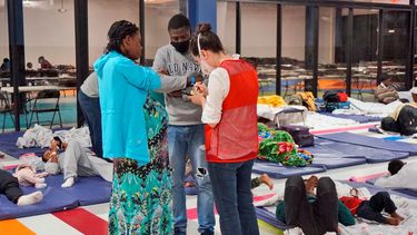 Una voluntaria ayuda a una mujer embarazada y su pareja dentro del Humanitarian Respite Center (Centro de Alivio Humanitario) el jueves 15 de diciembre de 2022